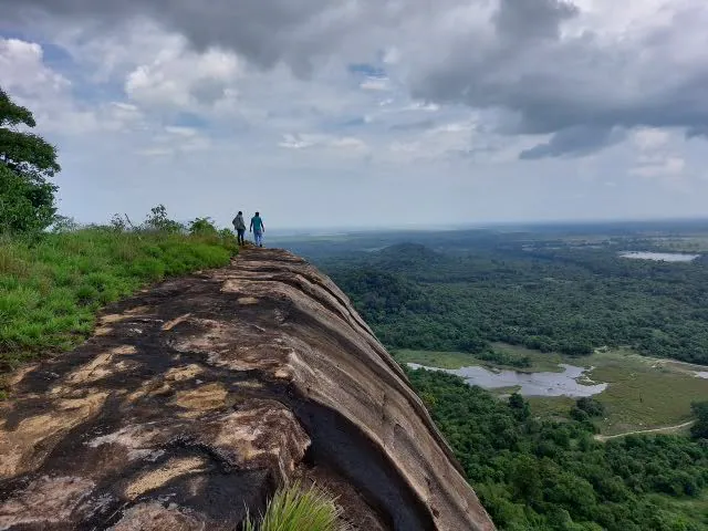 Two walkers on the granite ridge of Danigala above forest and lakes